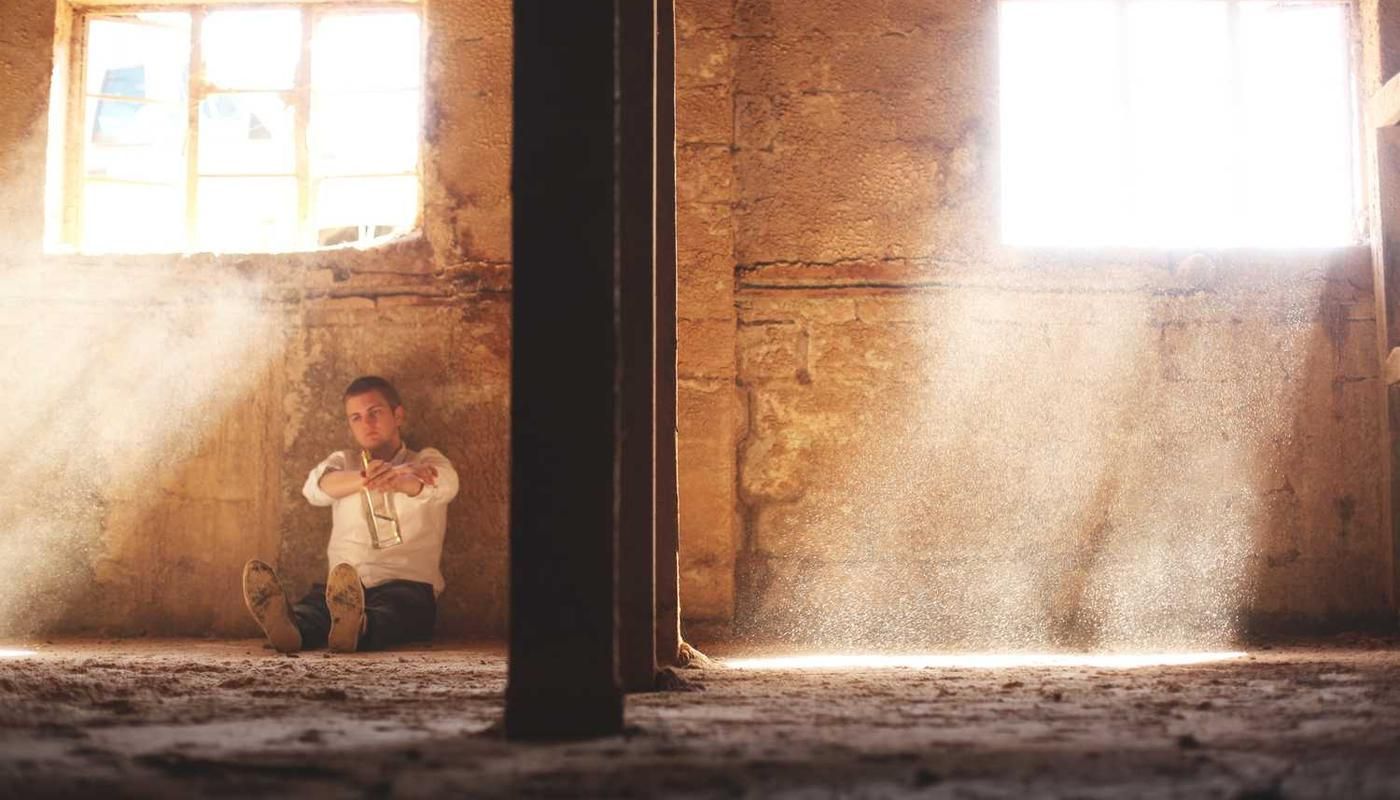 A man sits contemplatively in a sunlit, dusty room within an abandoned structure, evoking a sense of adventure and introspection for the Canopy Zipline Adventure in Panama City.