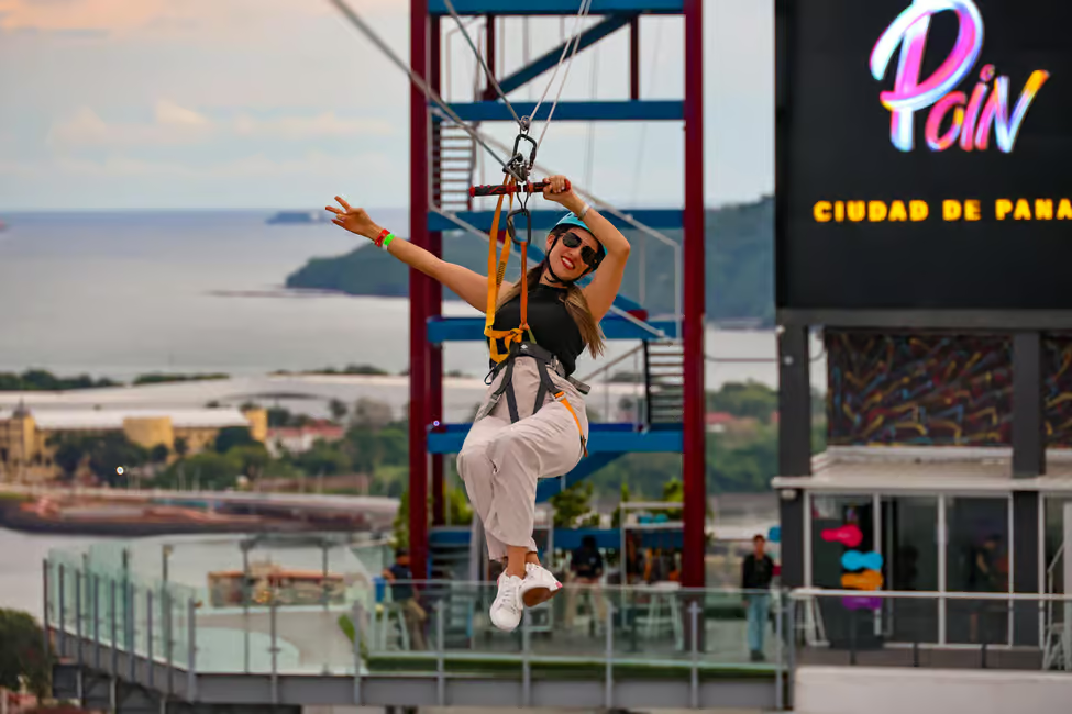 A woman ziplining over the Panama City skyline at Avenida Balboa, offering thrilling urban adventure with stunning city views.
